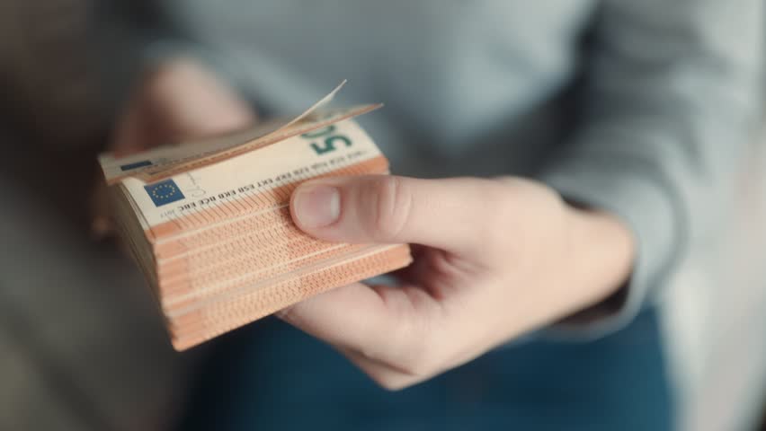 Close-up hands presenting euro banknotes, signifying wealth, financial planning, and income management within the euro currency framework.