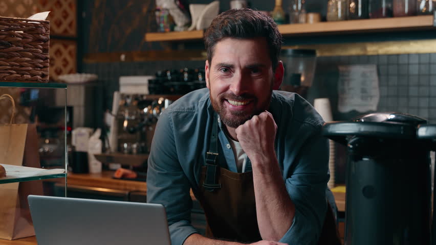 Carefree Caucasian entrepreneur barista worker browsing Internet using laptop online shopping employee drink coffee latte in cafeteria man waiter ordering equipment guy small business cafe male smile