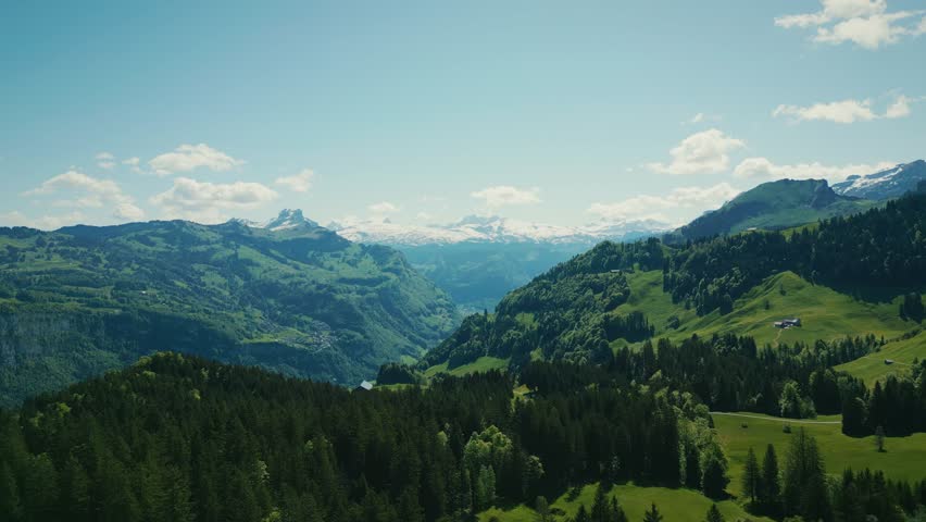 Picturesque landscape of Switzerland Alps mountains in spring covered by snow. Green mountain hills with snowy rocky mountain peaks on background, Stoos, Switzerland. Popular ski resort