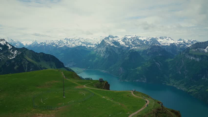 Picturesque view of lake Lucerne and snowy rocky mountains in Switzerland, aerial view. Flying over green mountains and lake with turquoise water in Stoos, Swiss