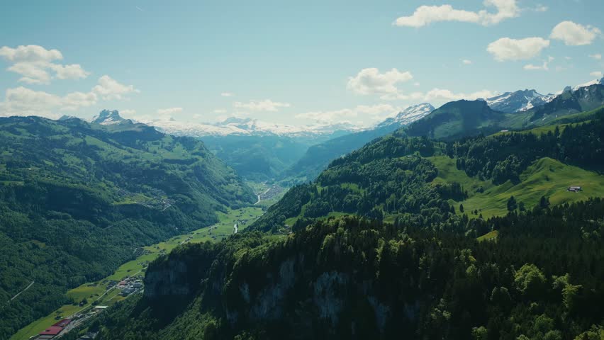 Picturesque snowy mountain peaks in Swiss Alps, Stoos. Green mountain hills with pine trees forest in Switzerland. Amazing nature landscape