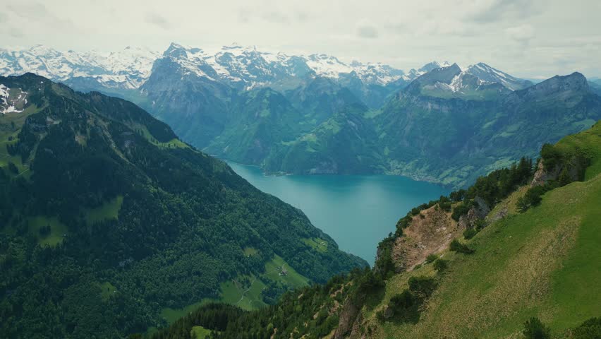Panorama of snowy rocky mountains and lake Lucerne in Swiss Alps. Picturesque aerial view of lake Lucerne with turquoise water and mountain peaks covered in snow on horizon