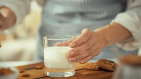 A person dips a chocolate chip cookie into a glass of milk, enjoying a relaxing moment at home. This comforting activity takes place in a cozy kitchen filled with light - Powered by Shutterstock - Get 15% off with code: PIKWIZARD15