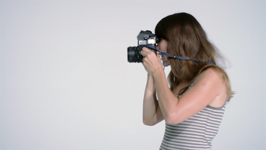 Attractive young woman taking photographs with large format camera in studio.