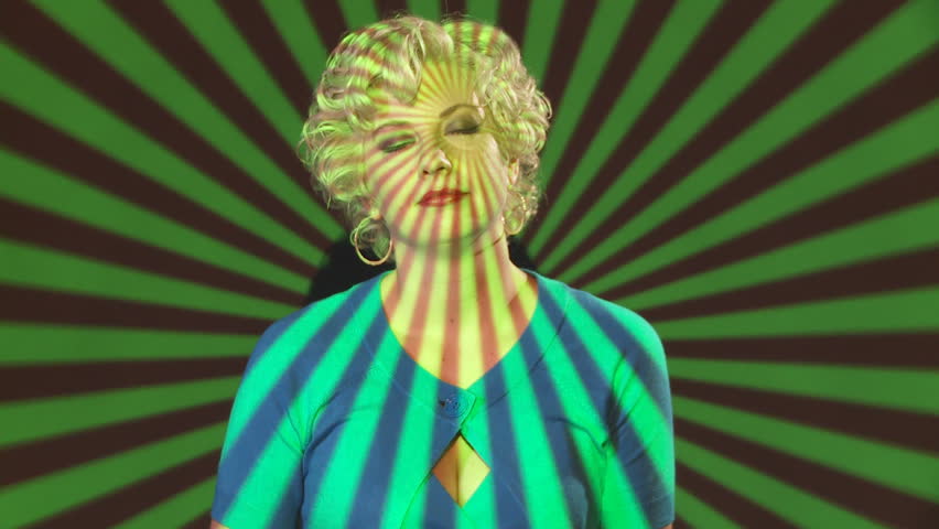 Blonde girl moves to unheard music in a projection of red, green, yellow
