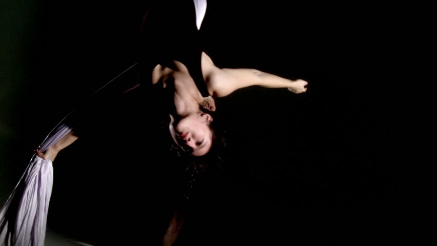 Aerial yoga practitioner flying upside down on silk. Close up with dark