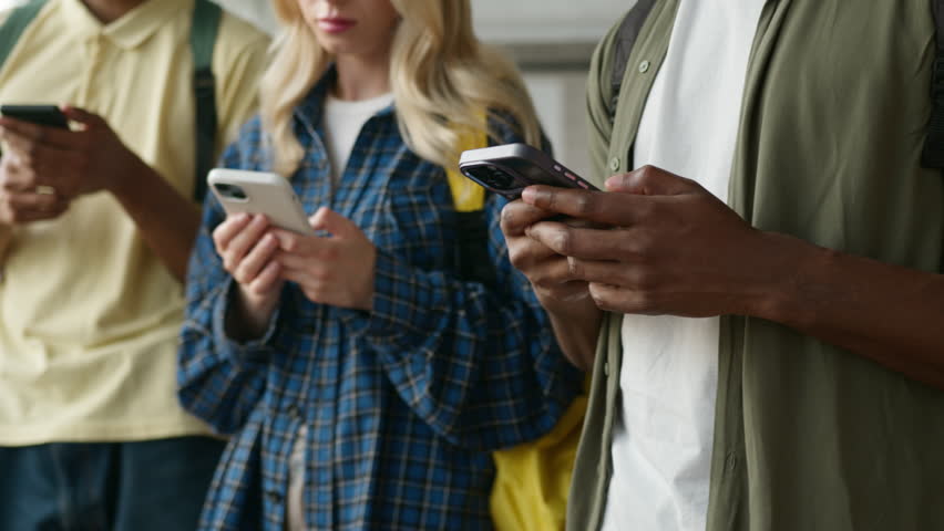 University college academy school four students unrecognizable multiracial friends male men Caucasian African American guys woman girl female using phones mobile addict gadgets addiction video game