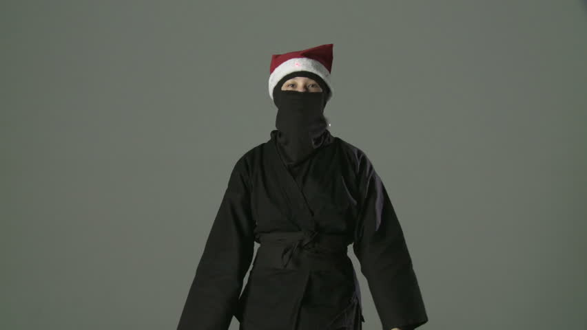Masked ninja assassin dances while wearing a Santa hat with blinking lights.