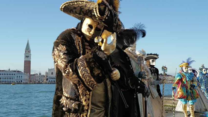 Venice, Italy - People dressed in carnival masks are photographed by tourists in the scenery of the ancient Venetian palaces