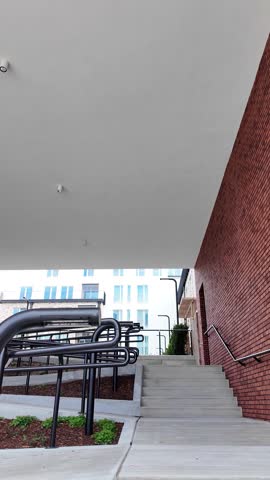 Concrete steps and metal handrails between brick buildings in a modern residential area, upward perspective