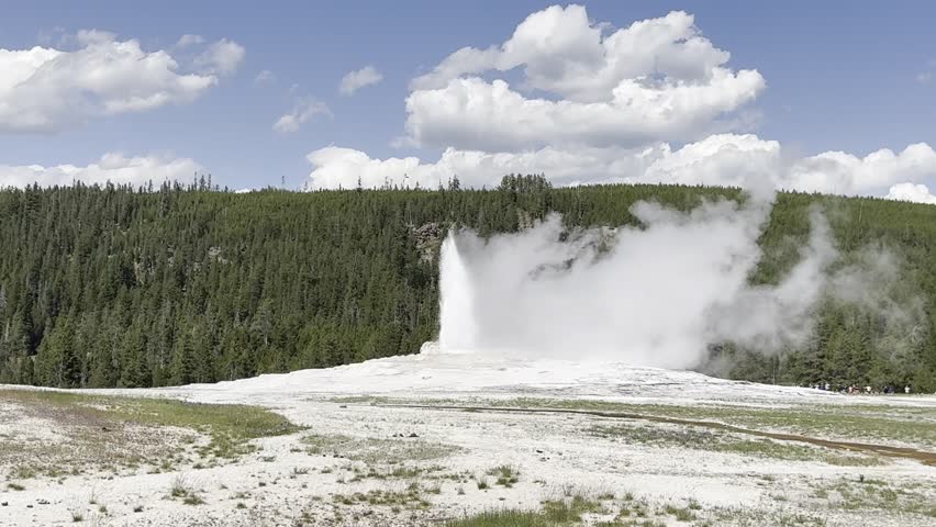 Scenic Old Faithful Geyser Eruption in Slow Motion with trees and mountain in the background 