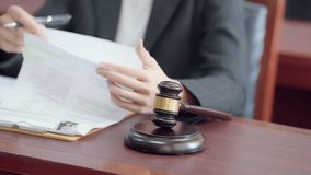A person in a suit is holding a gavel and looking at a piece of paper. The scene suggests a formal setting, possibly a courtroom or a meeting - Powered by Shutterstock - Get 15% off with code: PIKWIZARD15