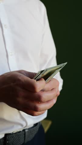 Individual counts cash with a focused expression in a business setting during daytime hours