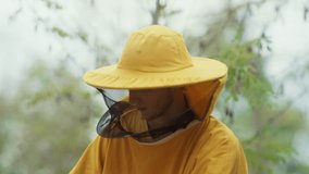 Blurred footage behind a beekeeper wearing a special yellow beekeeping helmet. - Powered by Shutterstock - Get 15% off with code: PIKWIZARD15
