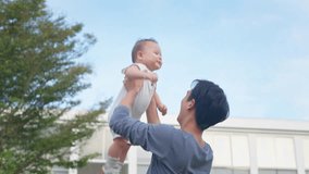 Asian young father holding and gently tosses baby boy outdoors in park. Attractive dad share a tender moment playing with newborn child, fostering a warm and loving family atmosphere in the garden. - Powered by Shutterstock - Get 15% off with code: PIKWIZARD15
