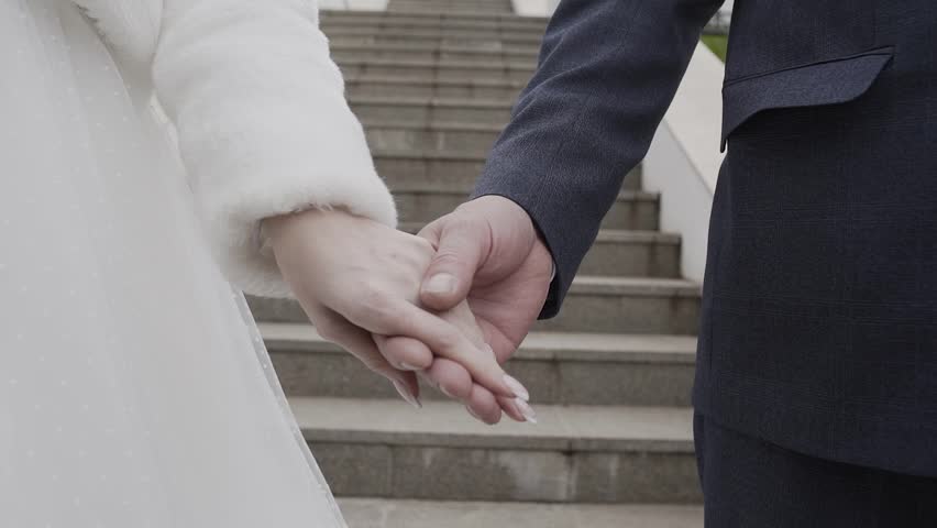 The bride and groom on their wedding day first tear their hands and then take them against the backdrop of a stone staircase