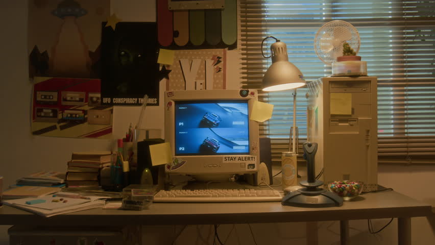 Handheld zoom in shot of 90s teenagers room with retro computer and racing video game playing on screen, copy space