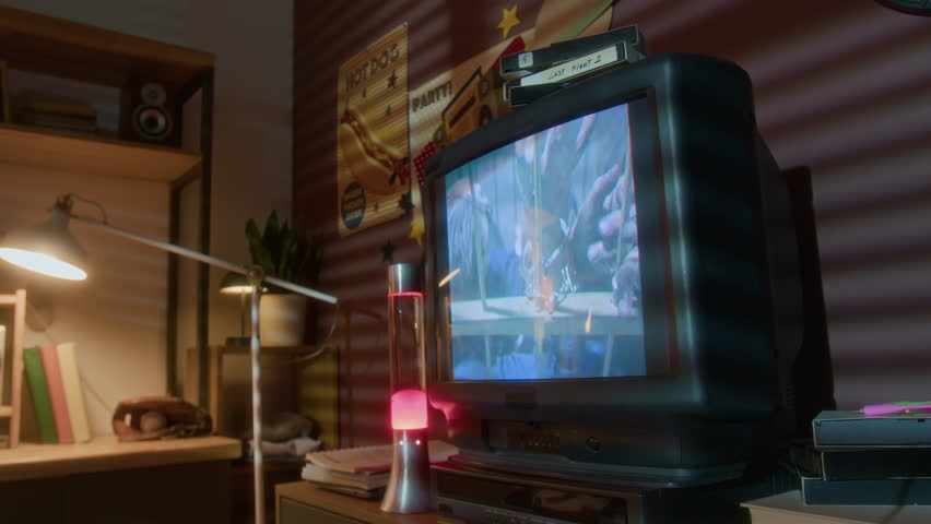 Closeup of old school hip-hop music video playing on screen of big retro TV in nostalgic setting with 90s interior and lava lamp, copy space