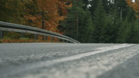Motorcyclist riding through frame on scenic forest road in autumn. Low angle static shot. Asphalt in the foreground with focus pull. Right to left. - Powered by Shutterstock - Get 15% off with code: PIKWIZARD15