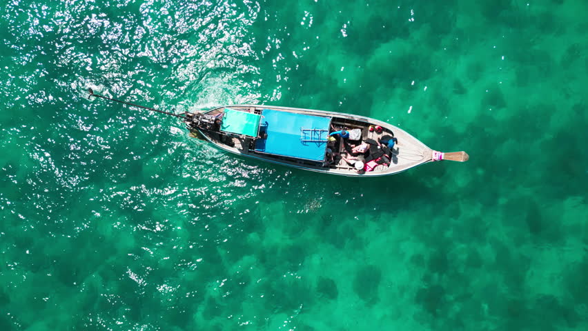 Drone shot above a sailboat gliding across the ocean under a summer sky, peaceful seaside adventure showcasing a boat navigating tropical waters with a scenic blue sky and sunlit waves.