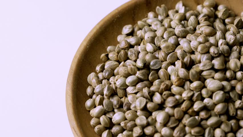 closeup pile of hemp seed in wood bowl rotation food white background texture footage 4k