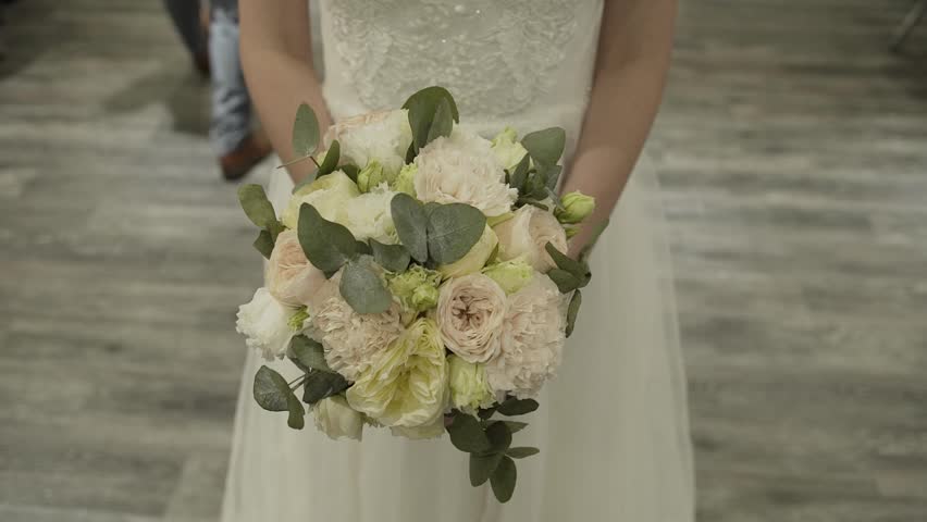 The bride holds a wedding bouquet in her hands