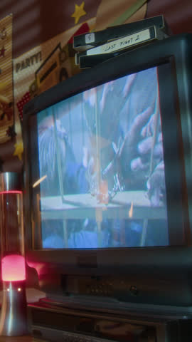 Vertical shot of music video playing on screen of big retro TV in nostalgic setting with 90s interior