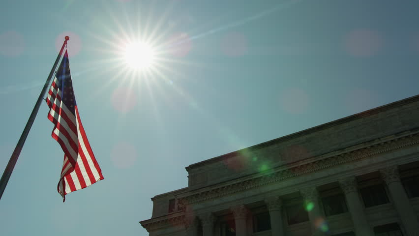 American Flag waving in front of Washington DC building on sunny day.
