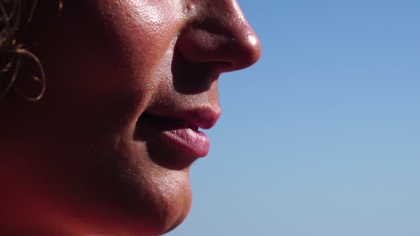 Woman, beach, lipstick - pretty lady applies protective lipstick for lip care. On beach, woman uses nourishing lipstick after day of sun exposure to refresh lips. Close up, Slow motion