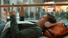 Teenage boy listening to music using smartphone resting in shopping mall - Powered by Shutterstock - Get 15% off with code: PIKWIZARD15