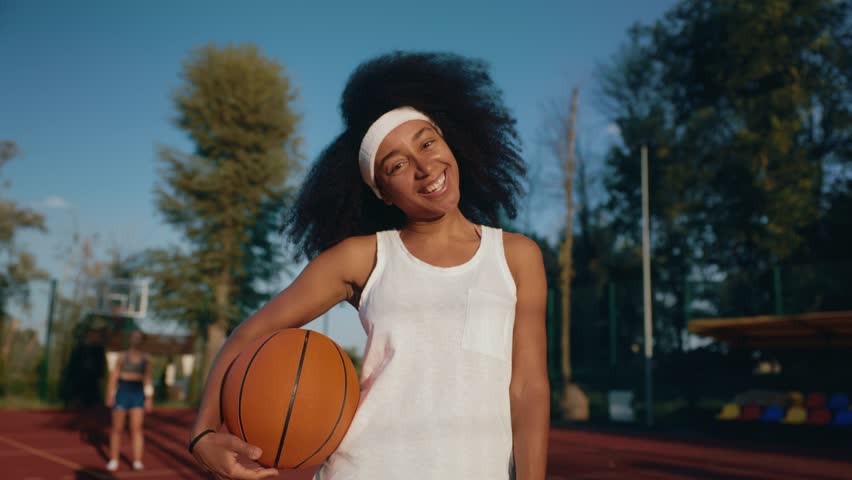 Teenage girl basketball player with ball over outdoor court background