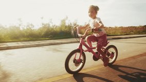 Girl rides bicycle on the empty asphalt street in urban area. Kid learns cycling on empty street in the town - Powered by Shutterstock - Get 15% off with code: PIKWIZARD15