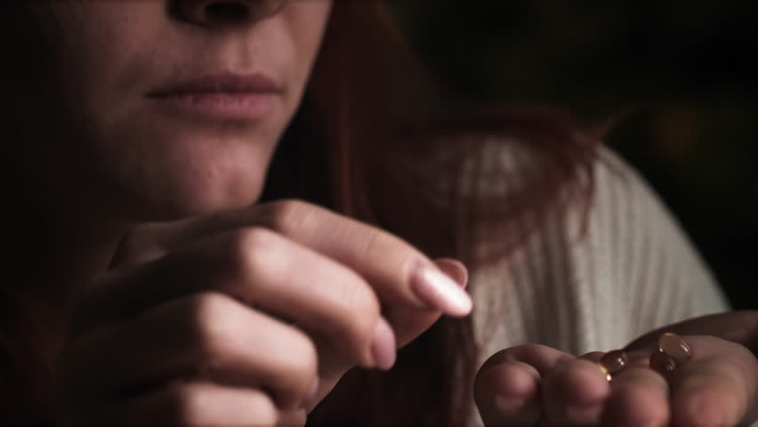 Close-up of young woman taking pills