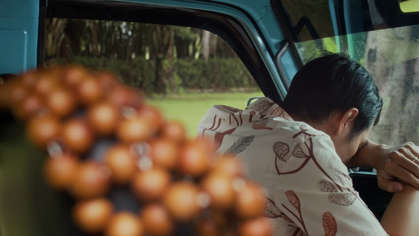 Unrecognizable exhausted black haired man sleeping on steering wheel after long road trip during nice warm weather