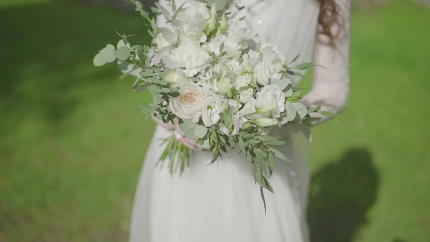A woman holds a wedding bouquet in her hands