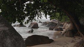 Tropical shore with stormy ocean waves crashing over granite rocks under dense foliage on a Seychelles beach - Powered by Shutterstock - Get 15% off with code: PIKWIZARD15
