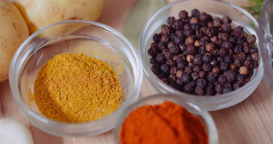 Fresh pepper, turmeric, and ground red paprika in small bowls on a rustic surface.