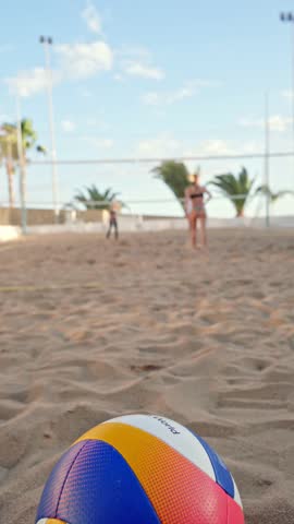 Beach volleyball training with colorful ball in foreground