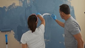 Couple painting wall together in a new home showing love and teamwork in an indoor setting, featuring a man and a woman creating a heart shape with paint. - Powered by Shutterstock - Get 15% off with code: PIKWIZARD15