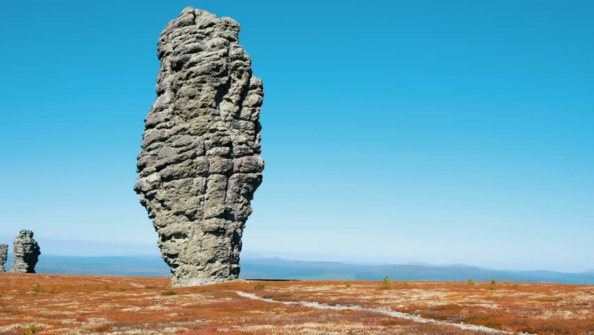 Majestic manpupuner rock formations stand tall against a vibrant blue sky, showcasing komi republic