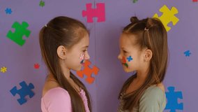 Adorable little girls show off their faces decorated with paper pieces of multicolored puzzles, as a sign of support for children with autism spectrum disorders. - Powered by Shutterstock - Get 15% off with code: PIKWIZARD15