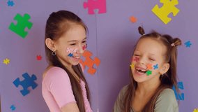 Funny laughing girls show off their faces decorated with pieces of multicolored puzzles. Preschool education. World Autism Day - Powered by Shutterstock - Get 15% off with code: PIKWIZARD15