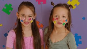Cute little girls on a background decorated with pieces of multicolored puzzles are blowing kisses, supporting children with autism. - Powered by Shutterstock - Get 15% off with code: PIKWIZARD15
