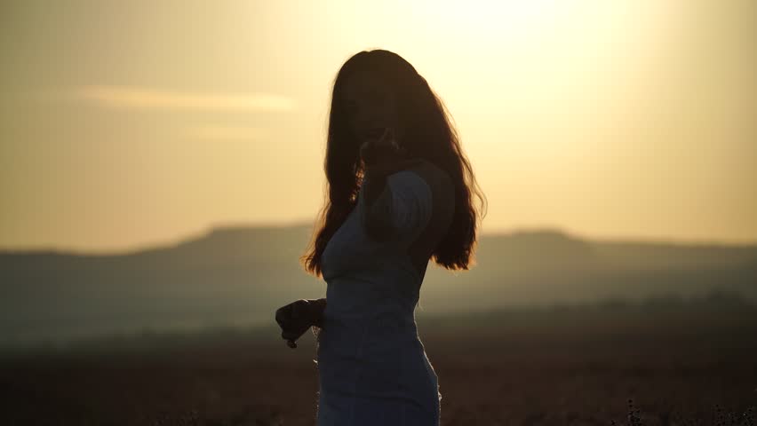 Woman Sunset Silhouette: Female gazes at evening sun in open field landscape to appreciate nature.