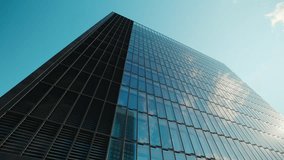 Office building facade covered with panoramic windows reflects clouds and clear sky in downtown block. Corporate company head quarter in urban environment. Architectural trends - Powered by Shutterstock - Get 15% off with code: PIKWIZARD15