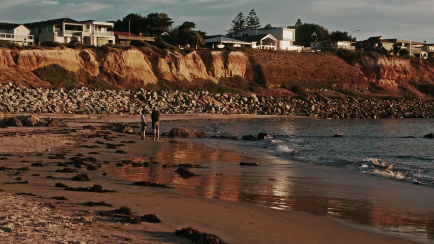 Retired Couple Walking Seaside Cliff Houses at Australian Sandy Beach at Sunset Blue Sky Clouds