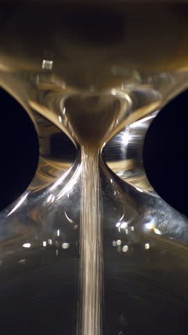 Vertical Timelapse of sand flowing and running out in an hourglass, extreme close up shot. Concept of lack of time.