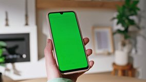 Girl hand tapping chroma key smartphone in living room apartment closeup. Unknown woman shopping online at green screen cellphone at home. Lady browsing application on mockup mobile phone indoors. - Powered by Shutterstock - Get 15% off with code: PIKWIZARD15