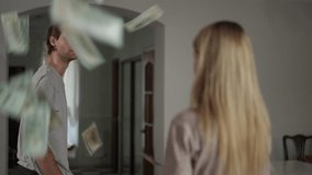 In slow motion, a blonde woman stands still, watching dollars fall around her as her partner walks away. The scene captures her reaction to the money floating in the air, with his back turned. The - Powered by Shutterstock - Get 15% off with code: PIKWIZARD15