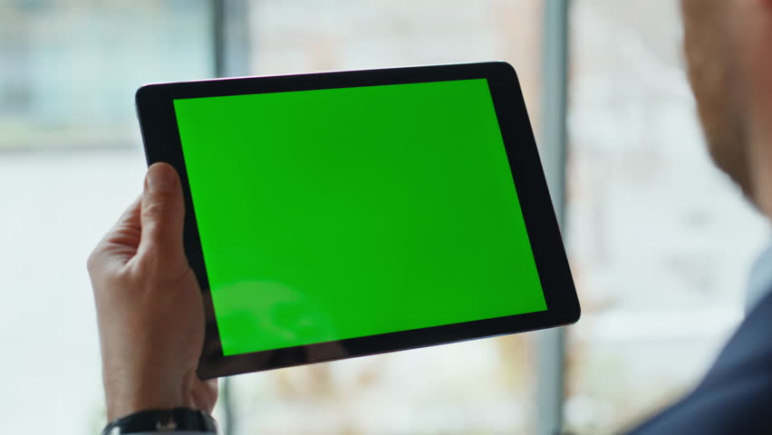 Employee swiping greenscreen tablet at company workplace closeup. Unknown businessman hands holding chroma key pad computer in office space. Man freelancer browsing business app on mockup gadget home.